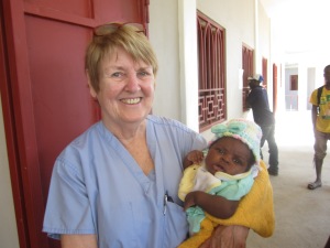 Team leader and nurse Kathy English holding an infant with a new handmade knitted cap on her head 